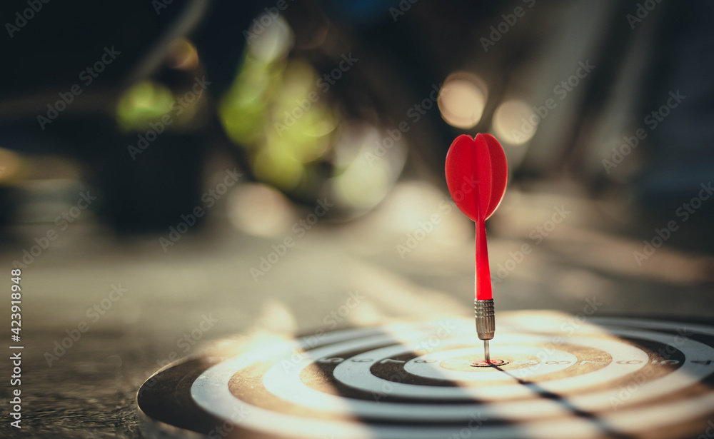 Close up shot of the dart arrow hit on bulleyes of dartboard to represent that the business reached the target with dark tone picture style. Target and goal as concept. Close up shot of the dart arrow hit on bulleyes of dartboard to represent that the business reached the target with dark tone picture style. Target and goal as concept.