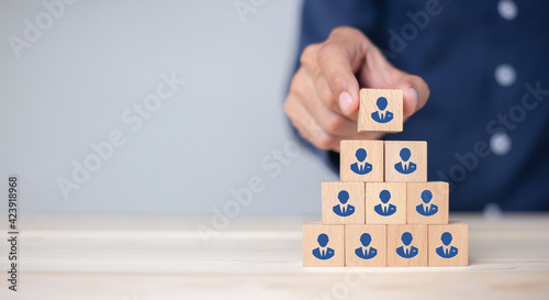 Concept of human resource management and recruitment business Hand put wood cube block on top pyramid To business success concept.