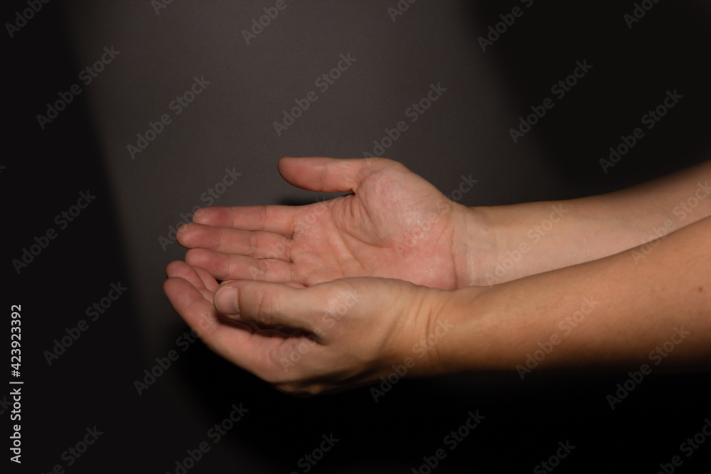 The man whose hand is praying on the dark background, selective focus.