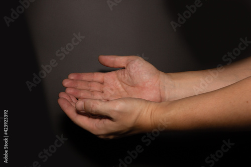 The man whose hand is praying on the dark background, selective focus.