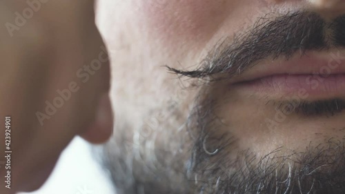 A man curls the ends of his mustache up closeup