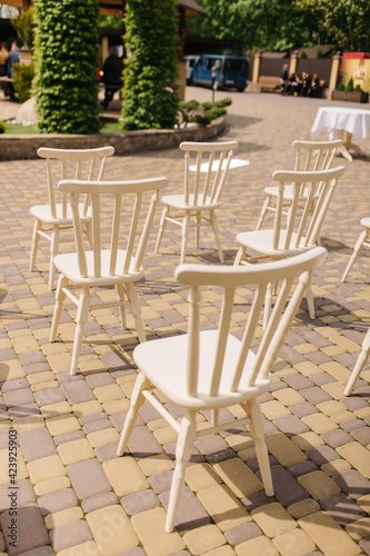 White wooden chairs stand in the yard. Chairs for a wedding ceremony