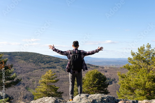 Man with backpack and open arms looking at the mountain
