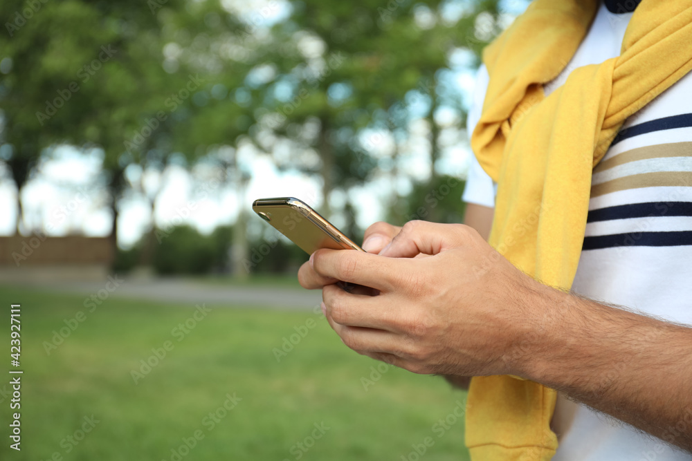 Man with smartphone in park on summer day, closeup