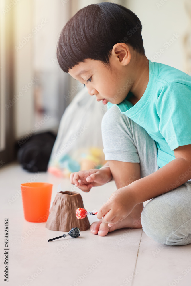 Cute little Asian boy plays with toy volcano happily on the floor of the children's room at home Cute little Asian boy plays with toy volcano happily on the floor of the children's room at home