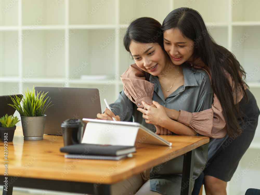 Lovely couple hugging while working on office desk in home office room Lovely couple hugging while working on office desk in home office room