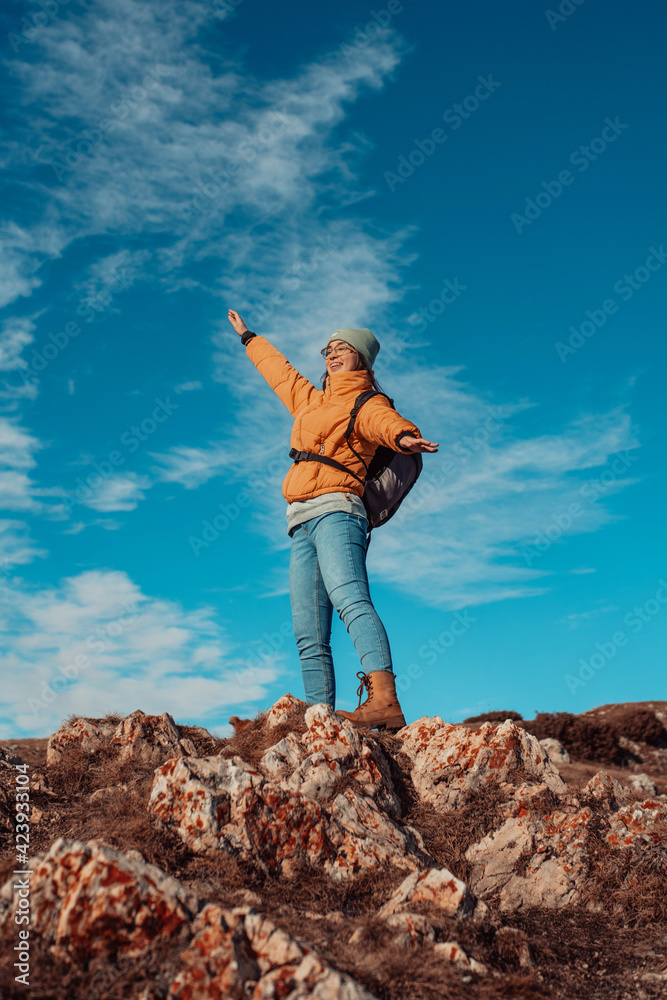 a hiking girl with a backpack on her back watches the morning from the top of the mountain