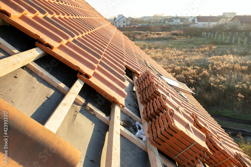 Stacks of yellow ceramic roofing tiles for covering residential building roof under construction.