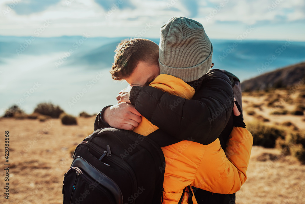 a young couple embracing standing on top of a mountain