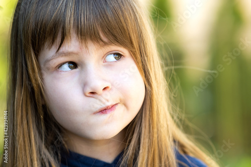 Fotografie Close up portrait of pensive cute brunette child girl in park