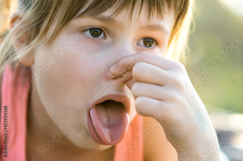 Canvas Print Close up of portrait beautiful child girl pinching nose and showing tongue