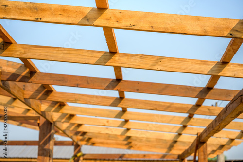 Photo of the wooden house roof and wooden roof structure on the construction site.