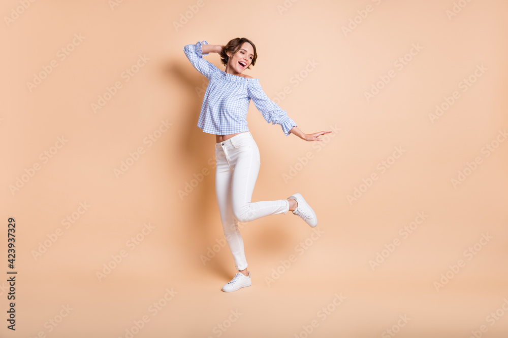 Fototapeta premium Full length photo of young excited girl happy positive smile have fun dance look empty space isolated over beige color background