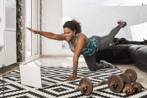 Black woman watching online tutorial during fitness workout at home
