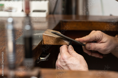goldsmith jeweler polishes and sands a silver ring with a metal file