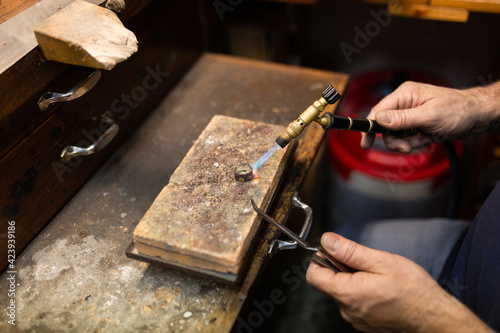 goldsmith jeweler soldering a silver ring on the workbench with a soldering.