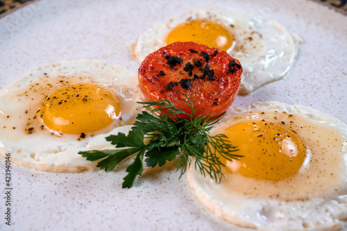 Fried eggs with tomato and herbs