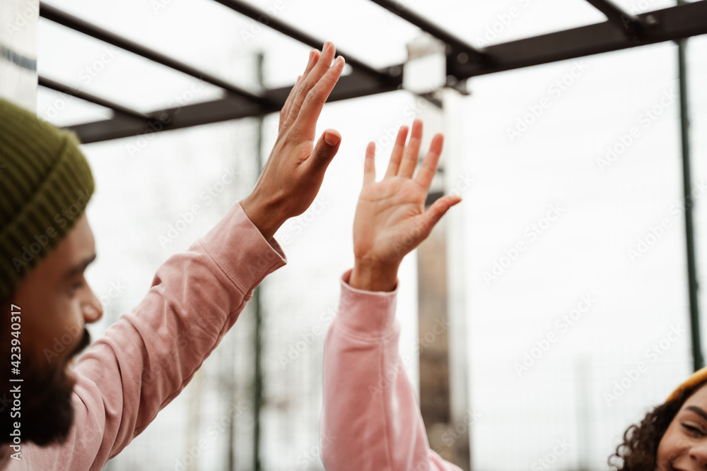 partial view of young african american athletes giving high five on blurred foreground partial view of young african american athletes giving high five on blurred foreground