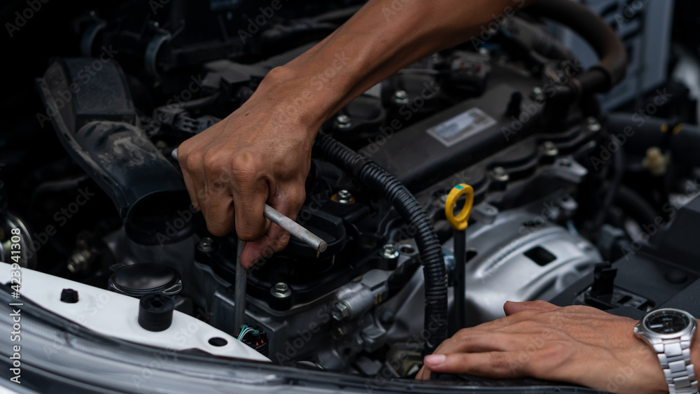 Young man repairing, maintaining and checking cars in a home car repair garage. Car service business concept. Young man repairing, maintaining and checking cars in a home car repair garage. Car service business concept.