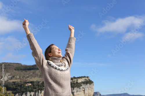 Excited woman celabrating raising arms in the mountain