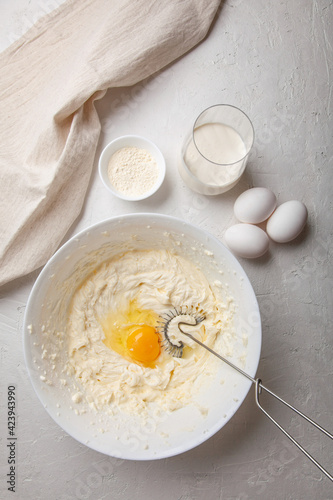 Bowl with cream cheese and egg for kneading dough. Ingredients for cooking Basque Spanish burnt Saint Sebastian cheesecake. Cream cheese, sugar, eggs, flour and cream. Recipe step by step