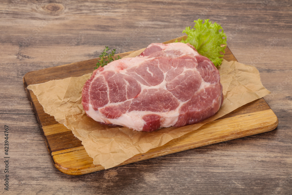 Raw pork steak over wooden board