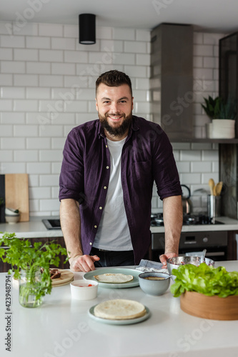 Happy Young Man ready to cook healthy fresh food at home in the kitchen, portrait, copy space