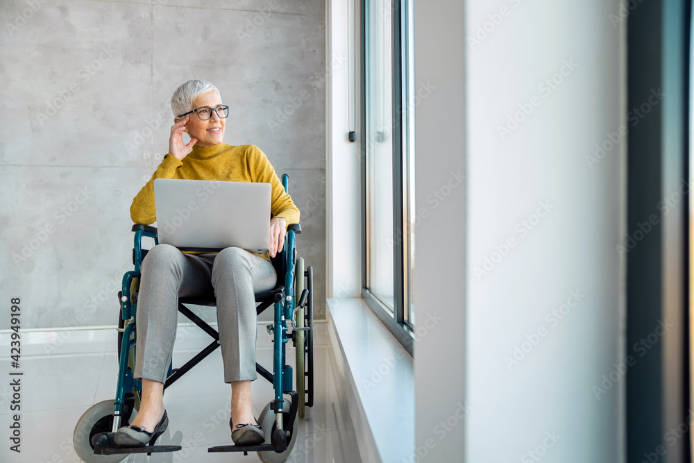 Senior business woman in wheelchair working in office Senior business woman in wheelchair working in office