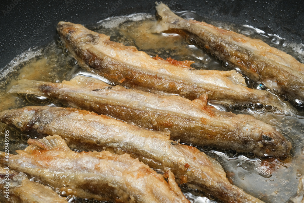 Fried fish in a frying pan. Capelin fried in oil with crispy breading. Shallow depth of field Fried fish in a frying pan. Capelin fried in oil with crispy breading. Shallow depth of field