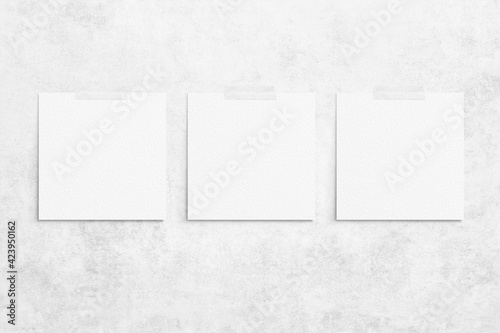 Composition of 3 white square watercolor sheets of paper glued with scotch taped on a concrete background. Advertising board, poster mockup on the wall for your design. Flat lay, top view, copy space