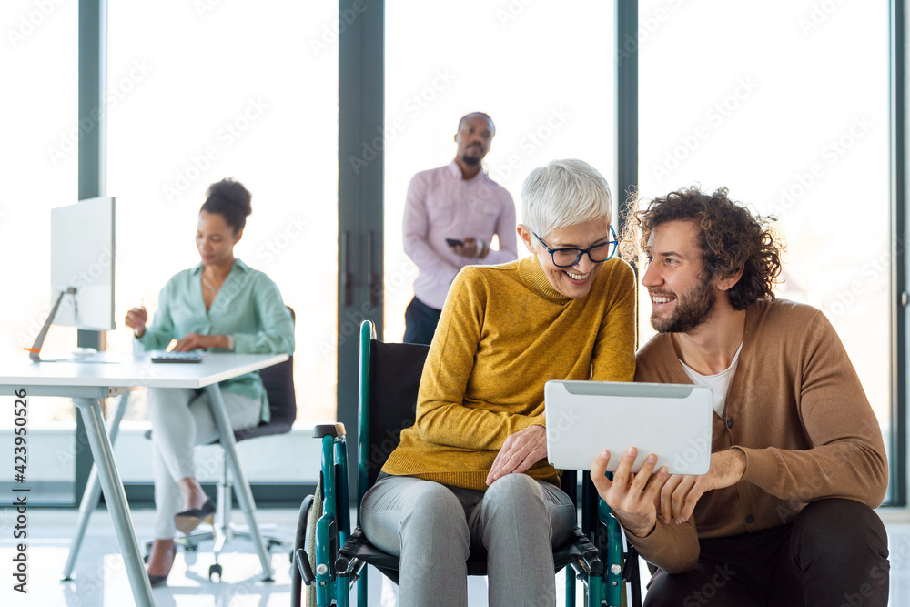 Business people with disability in wheelchair working together in office Business people with disability in wheelchair working together in office