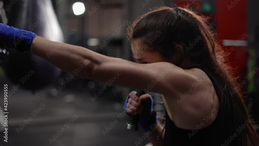 Female boxer strikes using dumbbells at boxing gym Female boxer strikes using dumbbells at boxing gym