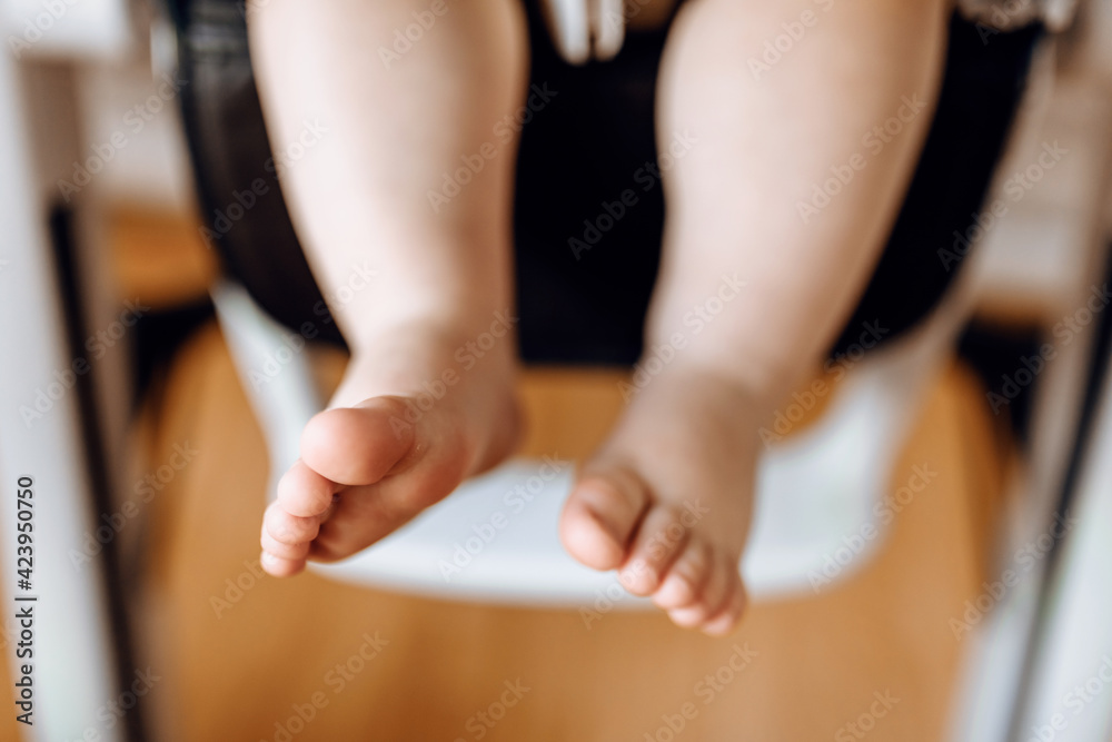 Close-up of little baby feet on highchair Close-up of little baby feet on highchair