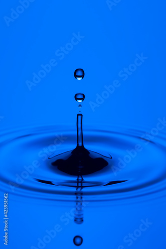 Close-up Macro Shot of Several Blue Water Droplets On Tranquil Water Surface.