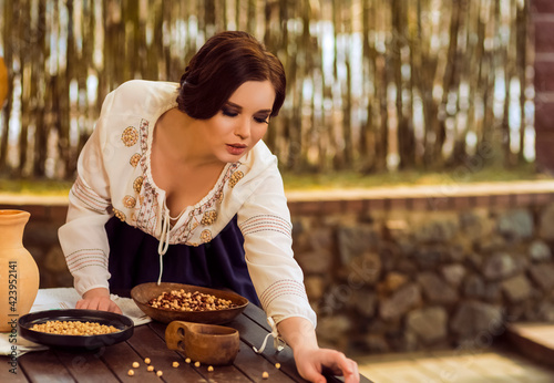 Sexy Caucasian Female in Rural Decorated Dress Posing with Wooden Plates Filled with Frigole Beans