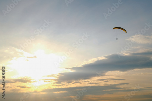 Paraglider flying into the sunset. Sky and sun landscape.