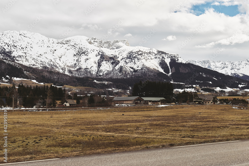 Snowing mountains Alps and little france village near road.