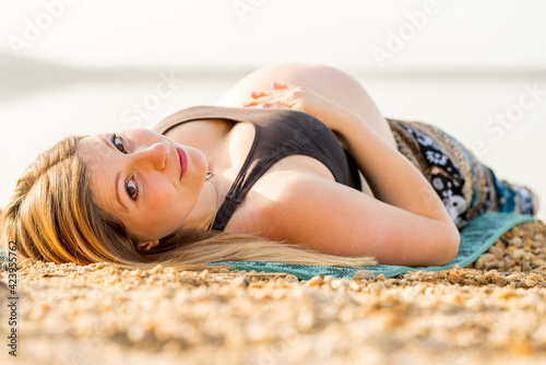 Happy pregnant woman lying on a beach