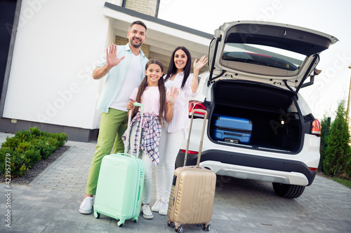 Full length photo of handsome man attractive lady cute little girl arm palm wave stand near car bags outdoors