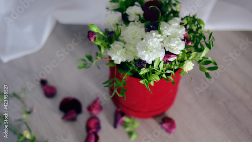 Flowers in a red box are on the floor, red roses with white flowers, a bouquet.