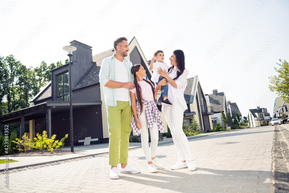 Full length body size view of nice adorable family mom dad walking with little kids having fun cottage town outdoor Full length body size view of nice adorable family mom dad walking with little kids having fun cottage town outdoor