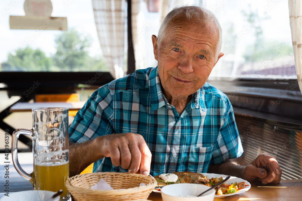 man posing with a mug of beer at lunch in a restaurant
