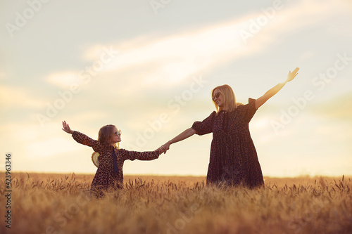 young mother and her daughter at the wheat field on a sunny day