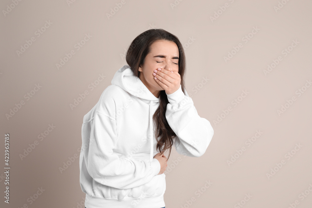 Young woman suffering from stomach ache and nausea on beige background. Food poisoning Young woman suffering from stomach ache and nausea on beige background. Food poisoning