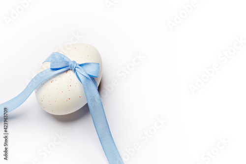 Minimal easter style design concept with creative dotted egg with the blue bow and ribbon isolated on the white background