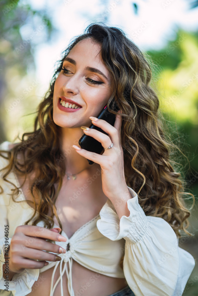 Chica joven guapa en un parque usando el smartphone y dando un paseo en primavera Chica joven guapa en un parque usando el smartphone y dando un paseo en primavera
