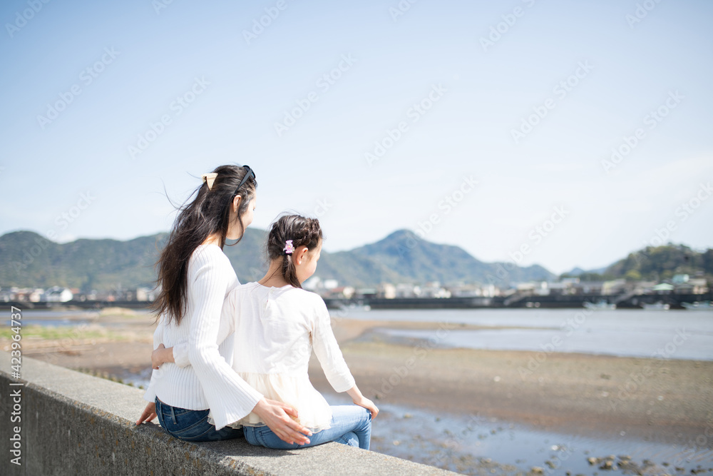 座って海を見る母と娘