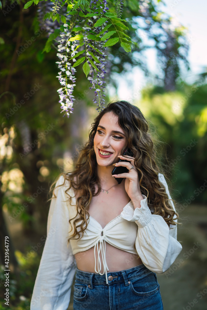Chica joven guapa en un parque usando el smartphone y dando un paseo en primavera Chica joven guapa en un parque usando el smartphone y dando un paseo en primavera