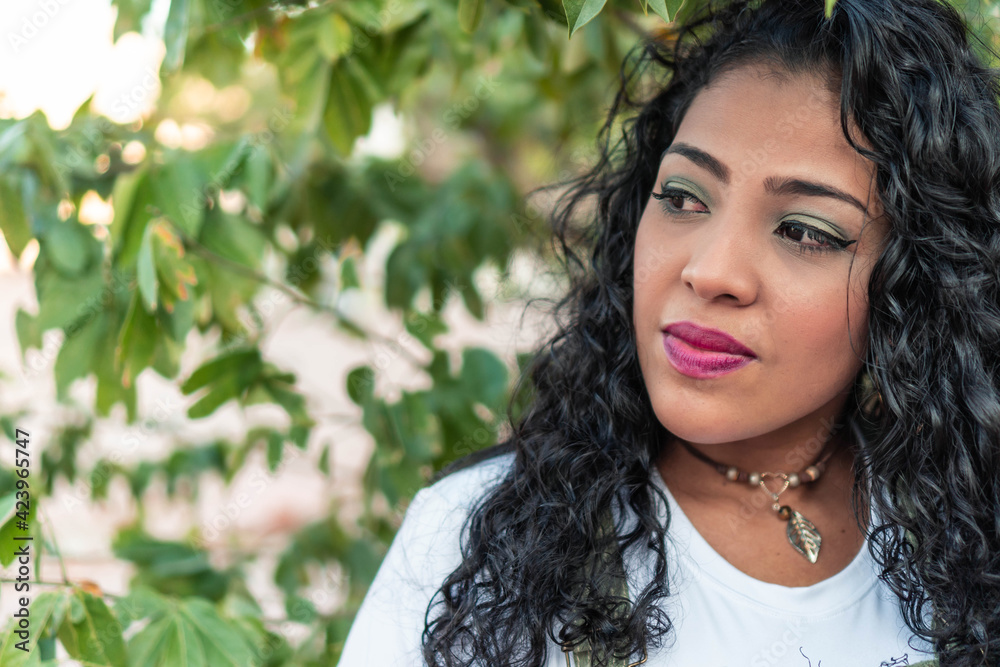 Portrait of a beautiful young woman with long curly hair and red lips posing outdoors. Portrait of a beautiful young woman with long curly hair and red lips posing outdoors.