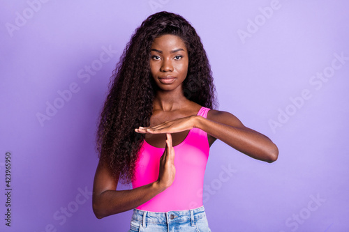 Photo portrait of african american woman showing time out sign isolated on pastel pink colored background
